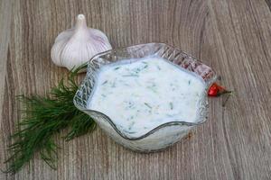 Tzatziki in a bowl on wooden background photo