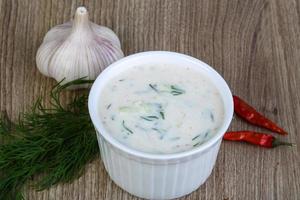 tzatziki en un recipiente sobre fondo de madera foto