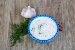 Tzatziki in a bowl on wooden background photo