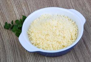 Shredded parmesan in a bowl on wooden background photo