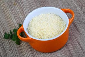 Shredded parmesan in a bowl on wooden background photo