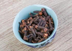 Cloves seeds in a bowl on wooden background photo