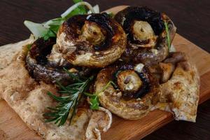 Baked champignons on wooden board and wooden background photo