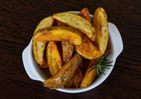 Roasted potato in a bowl on wooden background photo