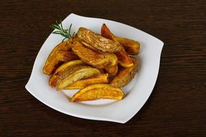 Roasted potato on the plate and wooden background photo