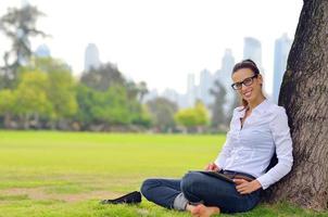 hermosa mujer joven con tableta en el parque foto