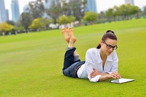 hermosa mujer joven con tableta en el parque foto