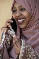 african  woman using smartphone wearing traditional islamic clothes photo