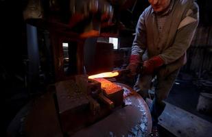 blacksmith manually forging the molten metal photo