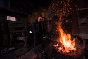 joven herrero tradicional trabajando con fuego abierto