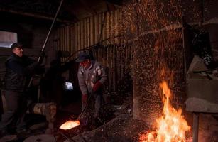 trabajadores del herrero que usan el martillo mecánico en el taller foto