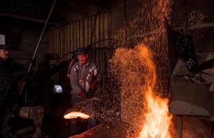 trabajadores del herrero que usan el martillo mecánico en el taller foto