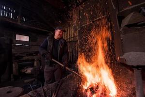 joven herrero tradicional trabajando con fuego abierto foto