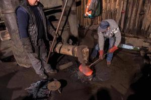 blacksmith workers using mechanical hammer at workshop photo