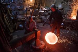 trabajadores del herrero que usan el martillo mecánico en el taller foto