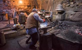 traditional blacksmith manually forging the molten metal photo