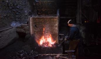 joven herrero tradicional trabajando con fuego abierto foto