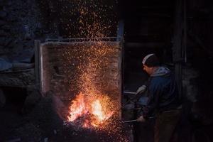 joven herrero tradicional trabajando con fuego abierto foto