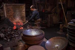 joven herrero tradicional trabajando con fuego abierto foto