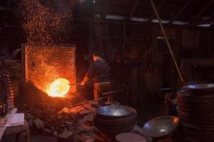 trabajadores del herrero que usan el martillo mecánico en el taller foto