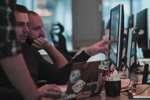 A photo of three men staring intently at a computer while sitting in a modern office. Selective focus