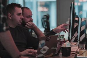 A photo of three men staring intently at a computer while sitting in a modern office. Selective focus