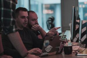 A photo of three men staring intently at a computer while sitting in a modern office. Selective focus