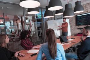 Leader give a business presentation at an office conference meeting, businessman coach mentor explains graph chart on board corporate group workshop training in boardroom. Selective focus photo