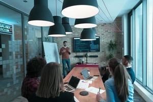 el líder da una presentación de negocios en una reunión de la conferencia de la oficina, el mentor del entrenador de negocios explica el gráfico a bordo del taller de capacitación del grupo corporativo en la sala de juntas. enfoque selectivo foto