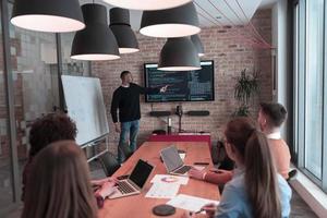 el líder da una presentación de negocios en una reunión de la conferencia de la oficina, el mentor del entrenador de negocios explica el gráfico a bordo del taller de capacitación del grupo corporativo en la sala de juntas. enfoque selectivo foto