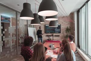 Leader give a business presentation at an office conference meeting, businessman coach mentor explains graph chart on board corporate group workshop training in boardroom. Selective focus photo