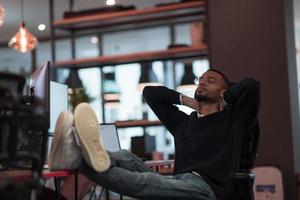 Young African American resting on chair with their feet on the table during work break photo