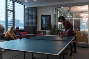 dos jóvenes emprendedores jugando tenis de ping pong en un espacio de oficina creativo moderno grupo de personas tienen reunión y lluvia de ideas en segundo plano foto