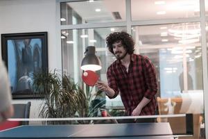Two young start up business man playing ping pong tennis at modern creative office space people group have meeting and brainstorming in background photo