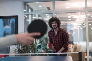 Two young start up business man playing ping pong tennis at modern creative office space people group have meeting and brainstorming in background photo