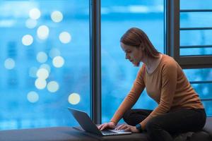 A young woman sitting in a modern space while working on a project on a laptop. Selective focus photo