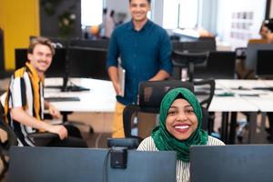 mujer árabe del equipo de negocios de inicio multiétnico que usa un hiyab en una reunión en una moderna oficina de diseño abierto interior lluvia de ideas, trabajando en una computadora portátil y de escritorio. enfoque selectivo foto