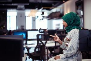 Multiethnic startup business team Arabian woman wearing a hijab on meeting in modern open plan office interior brainstorming, working on laptop and desktop computer. Selective focus photo