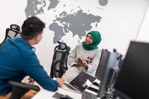 Multiethnic startup business team Arabian woman wearing a hijab on meeting in modern open plan office interior brainstorming, working on laptop and desktop computer. Selective focus photo