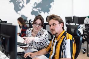 Business couple working together on project using tablet and desktop computer at modern open plan startup office. Selective focus photo