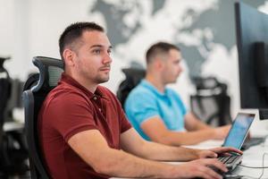 Group of Casual business man working on desktop computer in modern open plan startup office interior. Selective focus photo