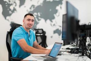 Young man sitting in office and working on desktop pc. Businessman looking at computer monitor while working in office. photo