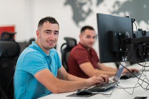 grupo de hombres de negocios casuales que trabajan en una computadora de escritorio en el moderno interior de la oficina de inicio de planta abierta. enfoque selectivo foto