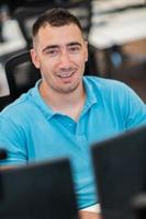 Casual business man working on desktop computer in modern open plan startup office interior. Selective focus photo