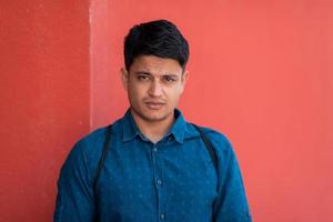 Startup business portrait of casual businessman with a blue shirt and backpack in front of red wall photo