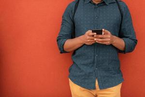 Startup business portrait of casual businessman with a blue shirt and backpack in front of red wall photo