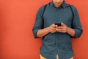 Startup business portrait of casual businessman with a blue shirt and backpack in front of red wall photo