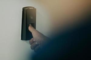 Man pressing fingerprint scanner on alarm system indoorsFinger print scan for unlock door security system photo