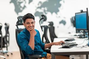 Casual business man working on desktop computer in modern open plan startup office interior. Selective focus photo