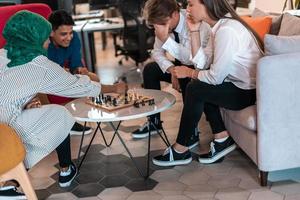 Multiethnic group of business people playing chess while having a break in relaxation area at modern startup office photo